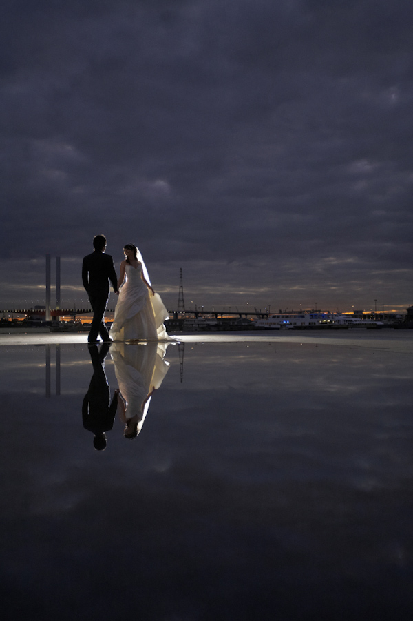 Bride in ball gown walks with groom at night - wedding photo by Jerry Ghionis